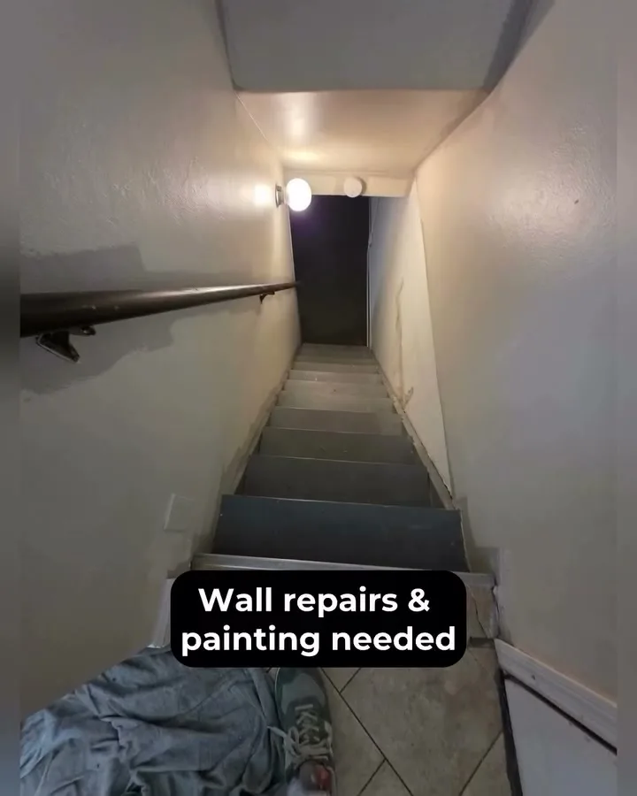 Before: basement stairwell with wall repairs and painting needed